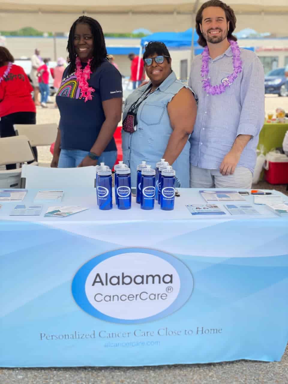 3 Alabama cancer care employees smile behind a vendor booth in Selma